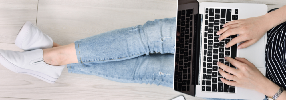 1-2-1 social media coaching with Karen Petrauskas. Image of a woman sitting crossed legged with a laptop